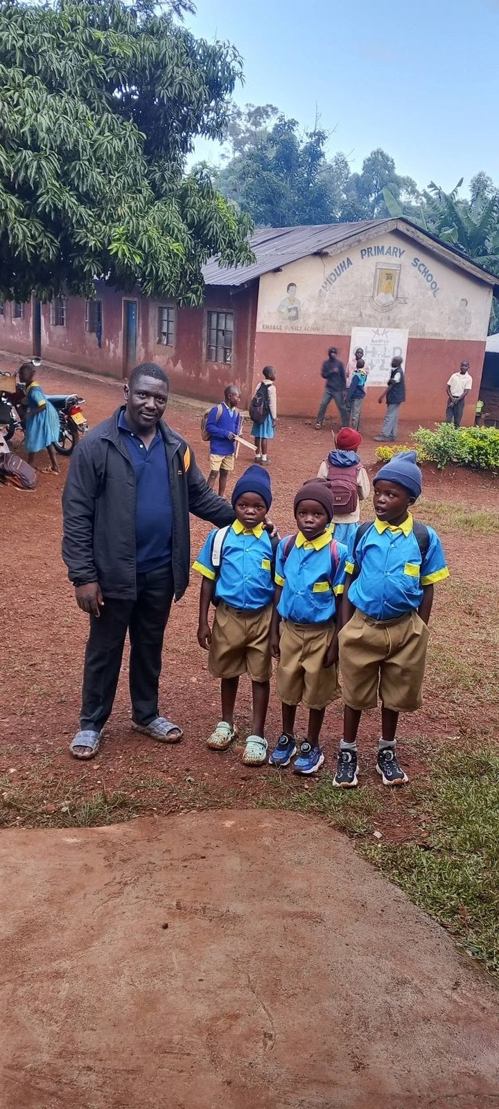 After: the three boys in new school uniforms, shoes and school bags, standing with a Foundation representative outside their primary school.