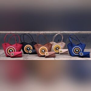 A row of handbags in red, black, brown, beige and blue, each with a round beaded medallion and a matching small purse.