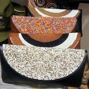 Leather clutch bags with curved, fully beaded flaps in white and gold, multicolour, and brown, black and white bands.