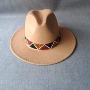 A camel felt fedora hat with a wide brim and a hand-beaded band of red, mustard, black and white triangles.