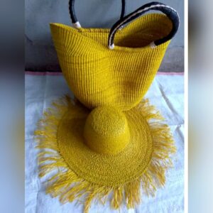 A bright yellow woven Ghanaian basket bag with black and white leather-wrapped handles, set with a matching wide-brimmed fringed sisal hat.