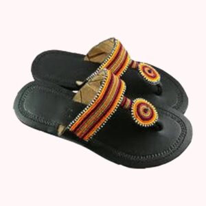 Black leather flat sandals with a wide strap of orange, red, yellow and green beadwork and a round beaded toe disc.