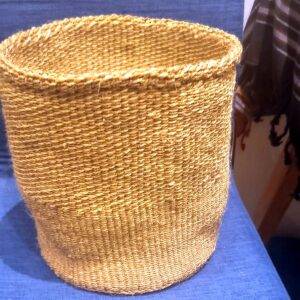 A round, open hand-woven sisal basket in natural golden fibre.