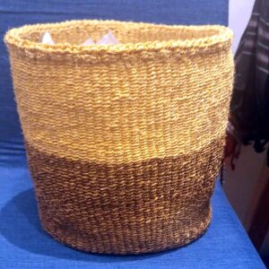 A round, open hand-woven sisal basket, natural at the top and dark brown at the base.