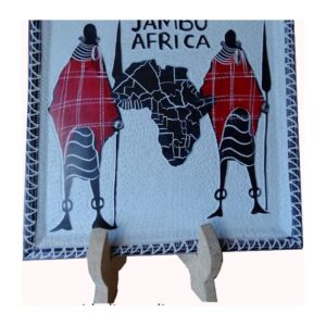 A square carved soapstone plate on a stand, painted with two Maasai figures in red shukas either side of a black map of Africa and the words Jambo Africa.