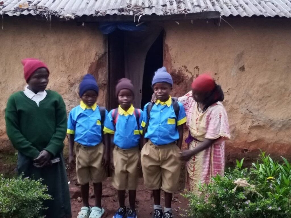 Three boys in school uniform standing with their family outside their home.