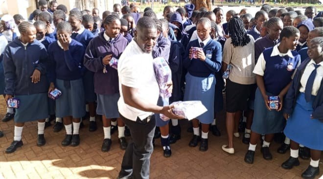A Cistern of Hope Foundation team member handing packs of sanitary pads to schoolgirls in uniform during a monthly school donation.