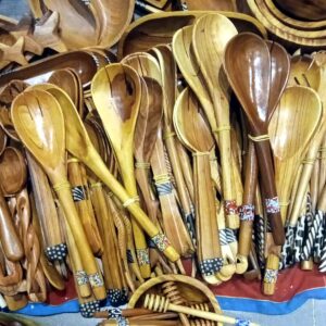Hand-carved wooden salad spoons and forks tied in pairs, with beaded and patterned handle bands.