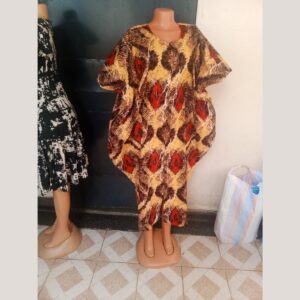 A loose, flowing boubou-style dress on a mannequin with wide batwing sleeves, in an African print of mustard yellow, brown and red diamond shapes with white crackle lines.