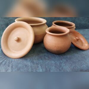 Handmade unglazed terracotta cooking pots with rounded bodies and matching lids with knob handles, set on a blue cloth.