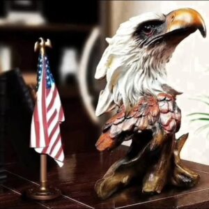 A hand-painted sculpture of an eagle head and shoulders with white head feathers, a golden hooked beak and russet wing feathers, rising from a carved wood-effect base.