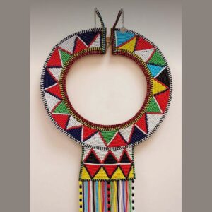 A round Maasai beaded collar necklace with a bold triangle pattern in red, white, blue, green, yellow and black, a beaded front panel and long multicoloured bead fringes, fastened with a hook clasp.