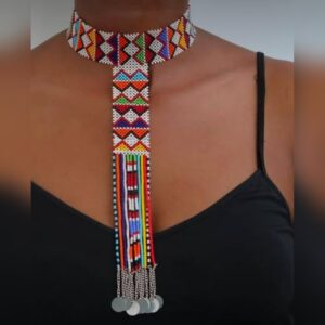 A Maasai beaded necklace worn at the neck: a close-fitting band of white beads with red, orange, blue, green and purple triangles, a long beaded drop panel in the same pattern, and multicoloured bead strands ending in silver discs.