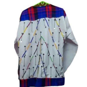 The back of a long-sleeved white shirt with a red and blue Maasai shuka check yoke and hem, decorated with lines of colourful beadwork and rows of hanging silver chains and discs.