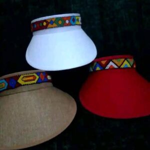 Three wide-brimmed sun visor hats in white, natural beige and red, each with a band of colourful Maasai beadwork in geometric patterns around the crown.