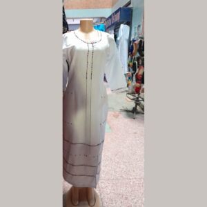 A long fitted white dress on a mannequin with three-quarter sleeves and colourful Maasai beaded trim around the neckline, down the front, on the cuffs and in rows across the skirt.