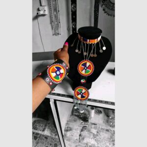 A Maasai jewellery set: a beaded choker with hanging silver chains and discs, a long pendant of round multicolour beaded medallions with chain fringe, and a matching black leather cuff with a large beaded medallion.