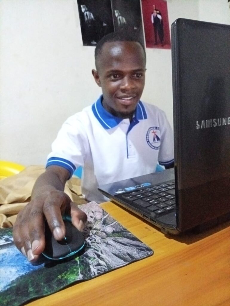 Dan smiling as he works on the laptop the Foundation helped him acquire for his photography business.