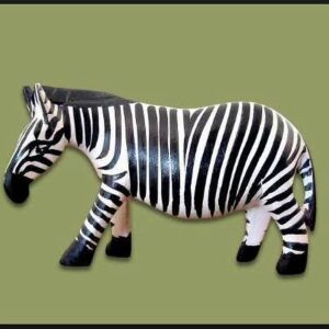 A hand-carved wooden zebra standing in profile, painted with bold black and white stripes, a black mane and black hooves.