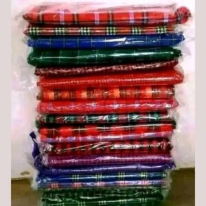 A tall stack of folded woven acrylic blankets in Maasai-style checked patterns, in red, blue, green, purple and orange, each wrapped in clear plastic.